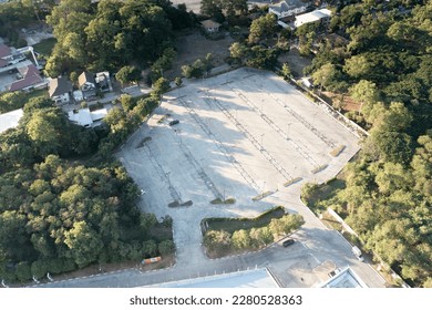 Car park in aerial view or top view. Empty space on concrete pavement floor at outdoor include many parking lot in row, line mark and lighting. Place outside airport, shopping mall for auto, vehicle.