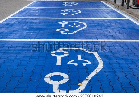 the car park is marked for parking and refuelling of electric cars and the road is painted blue. 