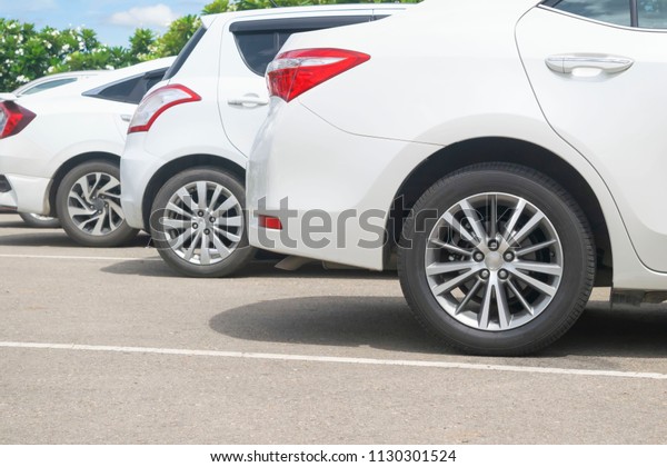 Car park on asphalt parking lot display alloy\
wheel of modern white cars. Transportation technology with green\
environment concept, close\
up\
