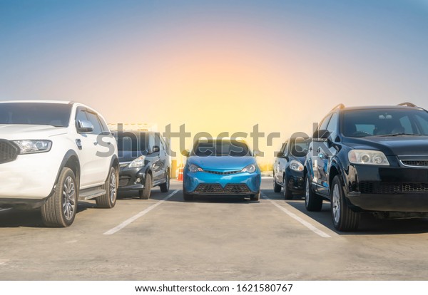 Car parked in\
asphalt parking lot and empty space parking with blue sky\
background. Outdoor parking lot with fresh nature, green\
environment transportation and\
technology\
