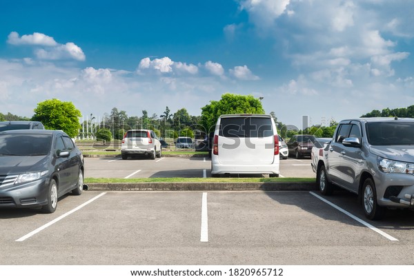 Car parked in\
asphalt parking lot and empty space parking with blue sky and cloud\
background. Outdoor parking lot with fresh nature, green\
environment transportation and\
technology\
