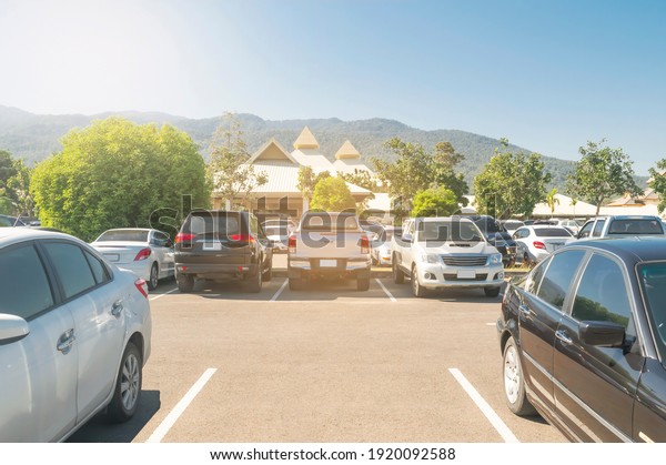 Car parked in asphalt parking lot and empty\
space parking in nature with trees, blue sky, mountain background\
.Outdoor parking lot with fresh ozone and eco friendly green\
environment concept\
