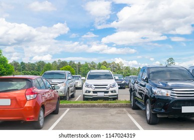 Car Parked In Asphalt Parking Lot And One Empty Space Parking  In Nature With Trees, Beautiful Cloudy Sky Background .Outdoor Parking Lot With Fresh Ozone And Green Environment Concept
