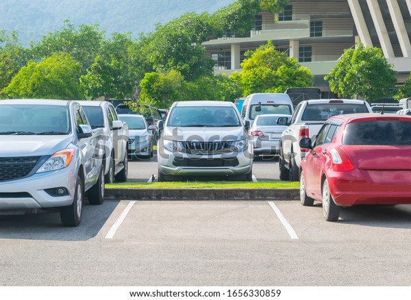 Car parked in\
asphalt parking lot and one empty space parking  in nature with\
trees and mountain background .Outdoor parking lot with fresh ozone\
and green environment\
concept\
