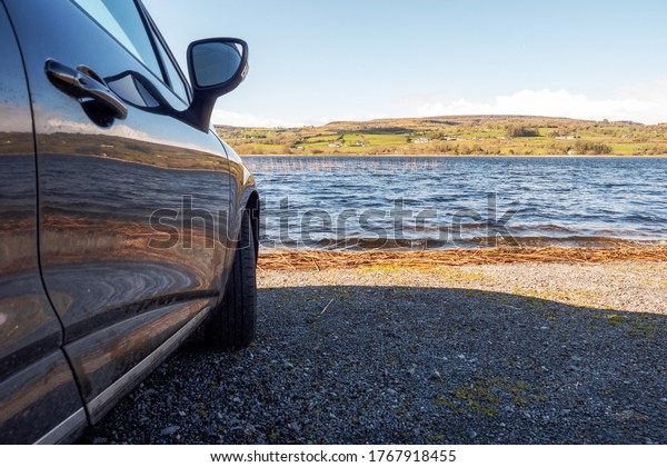 Car  parked by a lake, lake\
reflection on a side of the car. Concept travel, outdoor\
activity.