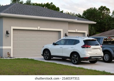 Car parked in front of wide garage double door on concrete driveway of new modern american house - Shutterstock ID 2160197311