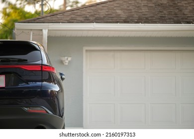 Car Parked In Front Of Wide Garage Double Door On Concrete Driveway Of New Modern American House