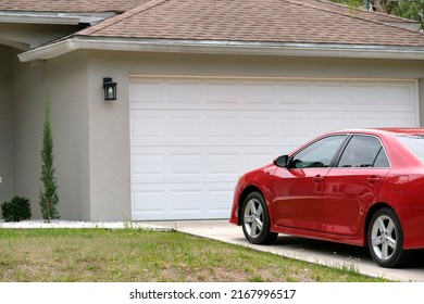 Car Parked In Front Of Wide Garage Double Door On Concrete Driveway Of New Modern American House