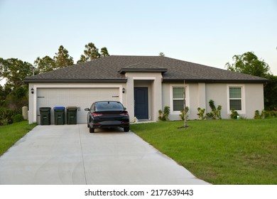 Car Parked In Front Of Wide Garage Double Door On Concrete Driveway Of New Modern American House