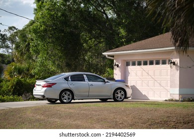 Car Parked In Front Of Wide Garage Double Door On Concrete Driveway Of New Modern American House