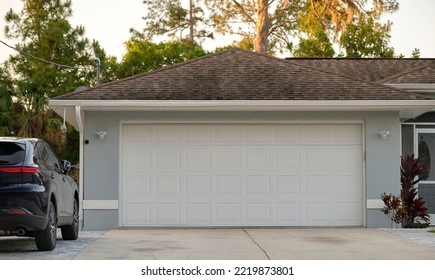 Car Parked In Front Of Wide Garage Double Door On Concrete Driveway Of New Modern American House