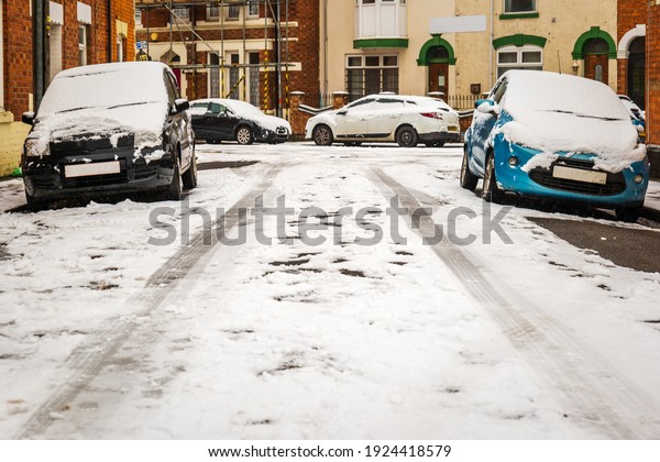 Car parked on british street under winter snow fall\
in england uk.