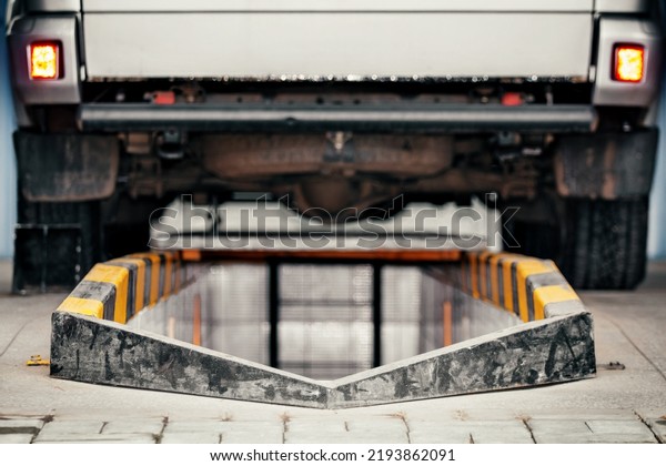 Car is parked on inspection pit in car\
service. Rear view of truck. Repair and maintenance of machine in\
workshop. Background.