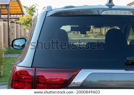 Car parked on the street in residential district, back view. Mock up of rear window for sticker or decals.