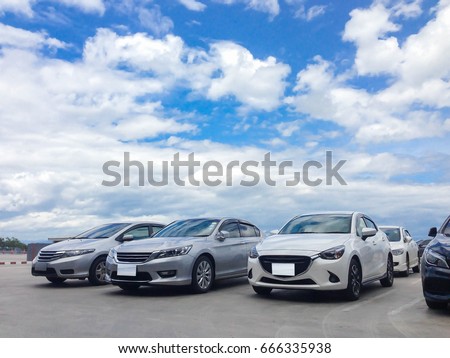 Car parked in parking lot at the rooftop of car parking building with white cloud and blue sky background