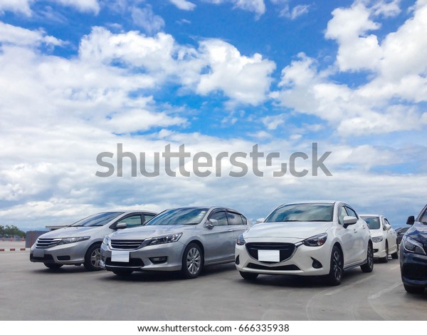 Car parked in parking
lot at the rooftop of car parking building with white cloud and
blue sky background