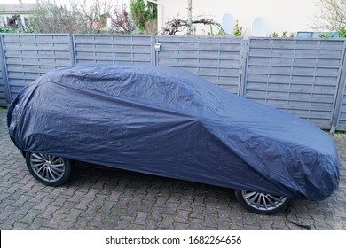 car parked under blue colored cover outside in winter