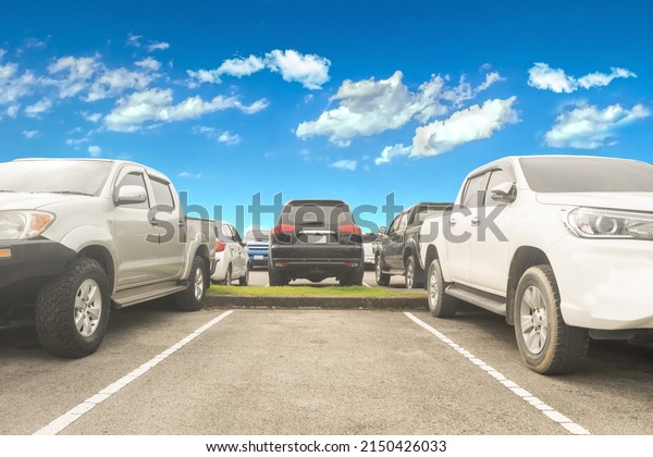 Car parking in the asphalt parking lot and\
empty space parking with white cloud and blue sky background.\
Outdoor parking lot with fresh nature and green environment of\
transportation and\
technology