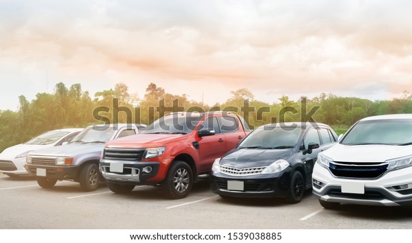 Car parking in\
asphalt parking lot with trees, white cloud and blue sky background\
. Outdoor parking lot with fresh ozone and green environment of\
transportation concept\
