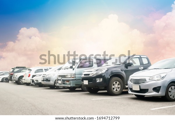 Car\
parking in large asphalt parking lot with beautiful sunset cloud\
and sky background. Outdoor parking lot with fresh ozone and green\
environment of transportation and\
technology\
