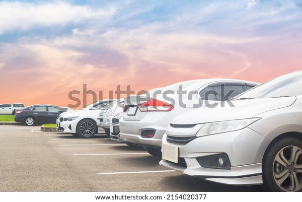 Car parking\
in large asphalt parking lot with beautiful sky background. Outdoor\
parking lot with nature fresh ozone and green environment of travel\
transportation business\
concept\
