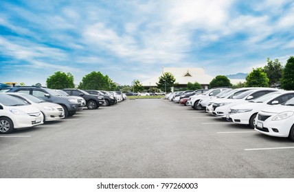Car parking in large asphalt parking lot with trees, white cloud and blue sky background in front of hall building. Outdoor parking lot with fresh ozone and green environment concept - Shutterstock ID 797260003