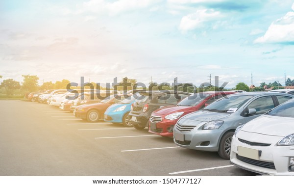 Car parking in large asphalt parking lot\
with trees, white cloud and blue sky background in sunny day.\
Outdoor parking lot with fresh ozone and green environment of\
transportation and\
technology\
