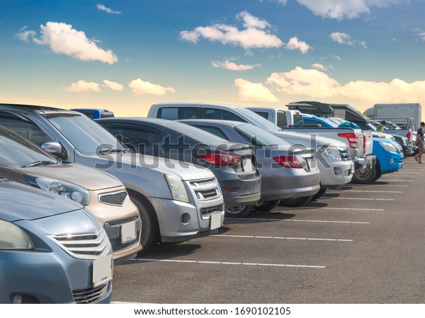 Car parking in large asphalt parking lot with\
white cloud and blue sky background. Outdoor parking lot with fresh\
ozone and green environment of transportation and modern technology\
concept\
\
