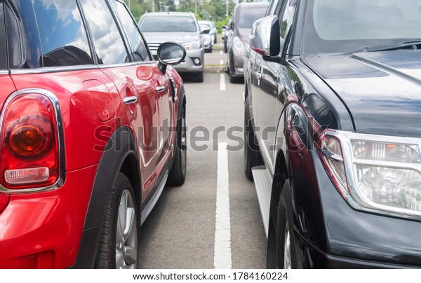 Car parking in parking\
lot. Red and black cars park in a row at outdoor asphalt parking\
lot background\

