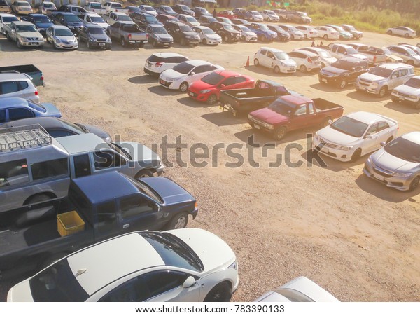 Car parking in parking lot. Row of various cars\
parked at outdoor parking lot on the soil ground background under\
sunlight, birds eye\
view\
\
