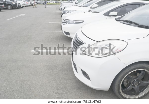Car parking in parking lot. Row\
of white cars parked at outdoor asphalt  parking lot\
background\
