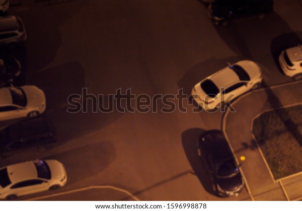 Car\
parking at night in a dark yard at residental aeria in a corner of\
a building. Aerial top view. Blurred\
background