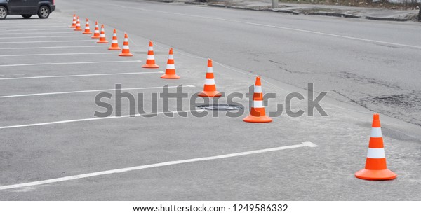 Car parking lot and orange traffic cone. Closed car\
parking lot with white mark and traffic cone on street used warning\
sign on road