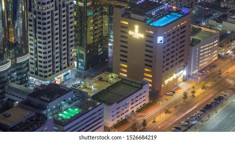 Car Parking Lot With Rooftop Swimming Pool Viewed From Above Night Timelapse, Aerial Top View At Financial District. People Relaxing. Dubai, UAE