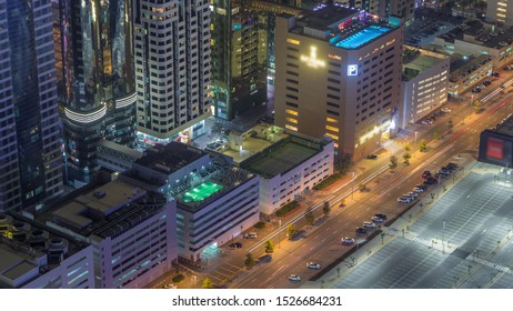 Car Parking Lot With Rooftop Swimming Pool Viewed From Above Night Timelapse, Aerial Top View At Financial District. People Relaxing. Dubai, UAE