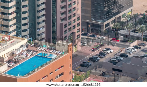 Car parking lot with rooftop swimming pool viewed\
from above timelapse, Aerial top view at financial district. People\
relaxing. Dubai, UAE