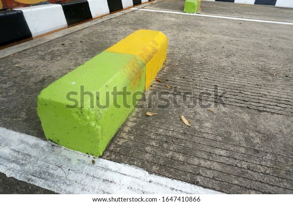 Car Parking Stopper \
from concrete with\
green and yellow color.                       \
