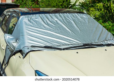 A Car In A Parking Lot With A Windscreen Covered With A Sunscreen Reflector On The Outside, To Protect The Plastic Part Of The Car Interior And The Glass From Direct Sunlight Or Ice, Protects The Car