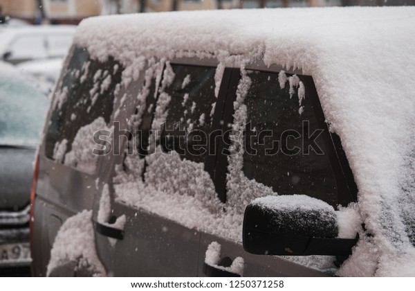 car is in Parking lot in winter covered with snow,\
heavy snowstorm hit city, storm warning, deep snowdrifts, tires are\
slipping and stuck, the problem is to leave, clean and brush off a\
lot of snow
