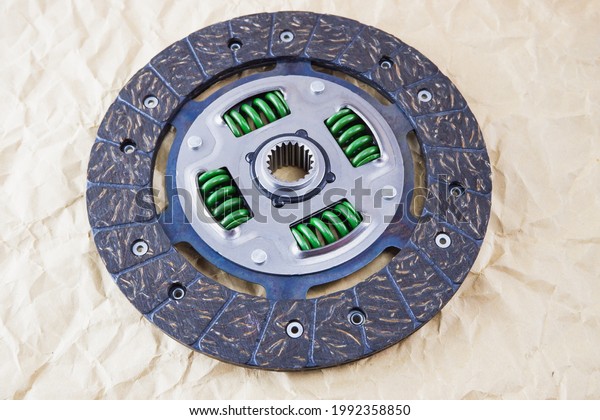 Car parts. Car clutch disc. Photo of a new clutch\
disc before installation on a car against a background of craft\
paper.