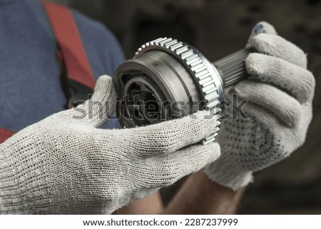 Car parts. Constant velocity drive. The structural element of the front suspension of the car. Before installation, a new spare part is in the hands of an auto mechanic.