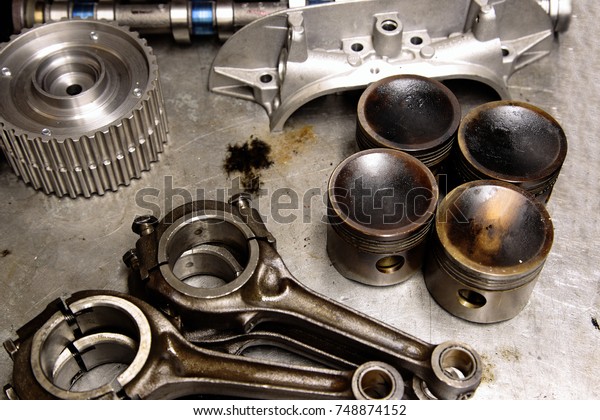 Car parts including piston, connecting rod and cam
shaft on a metal table