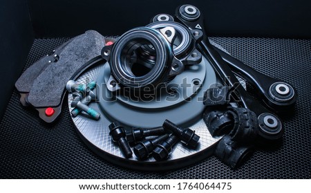 lot of car parts running gear: brake disc, pads and hub bearing with fasteners, isolated on a black background.