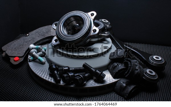 lot of car\
parts running gear: brake disc, pads and hub bearing with\
fasteners, isolated on a black\
background.