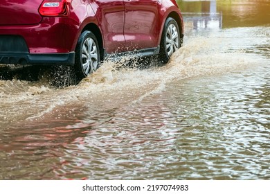 Car passing through a flooded road. Driving car on flooded road during flood caused by torrential rains. Flooded city road with a large puddle. Splash by car through flood water. Selective focus.
