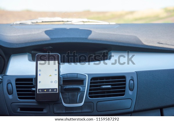 Car with phone navigator on a country road in\
summer. View from inside the\
car.