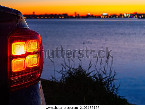 A\
car pictured near a lake. Picture taken at sunrise.\
