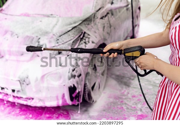 car in pink foam standing at a self-service\
car wash. car cleaning. removing dirt from the car. preparation for\
sale. washing for electric\
cars