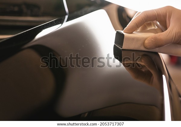 Car polish wax worker hand in protective\
gloves holds a polisher in the hand and polishes the car with nano\
ceramic, tools for\
polishing.