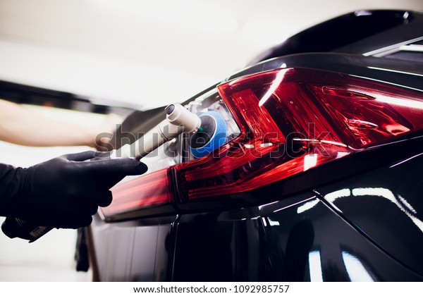 Car polish wax\
worker hands holding polisher and polish car detailing or valeting\
concept taillight red car